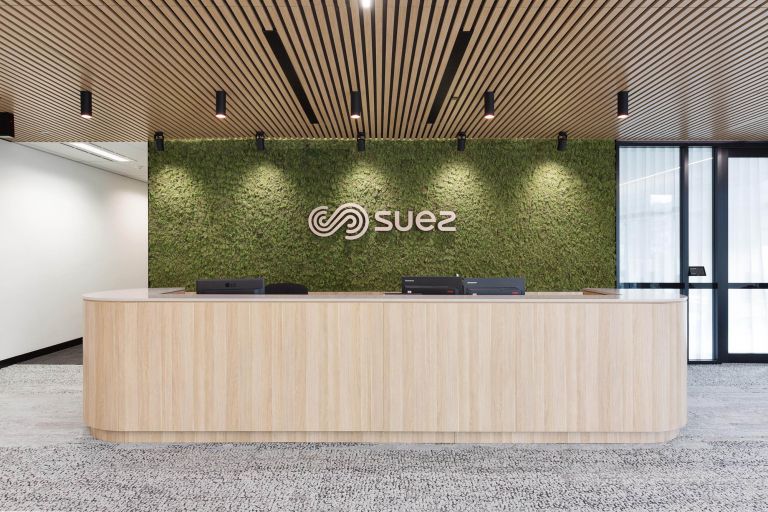 suez office fitout timber reception desk and green wall