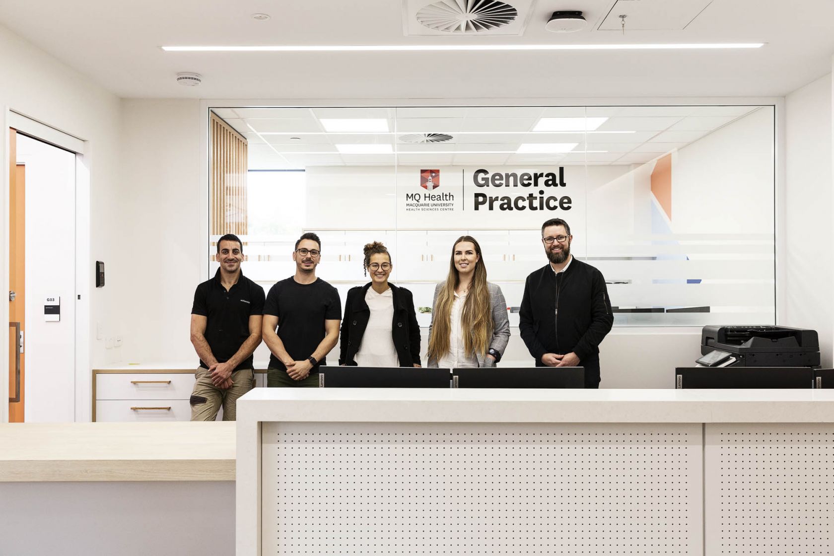 mq health general practive staff team standing in front of desk