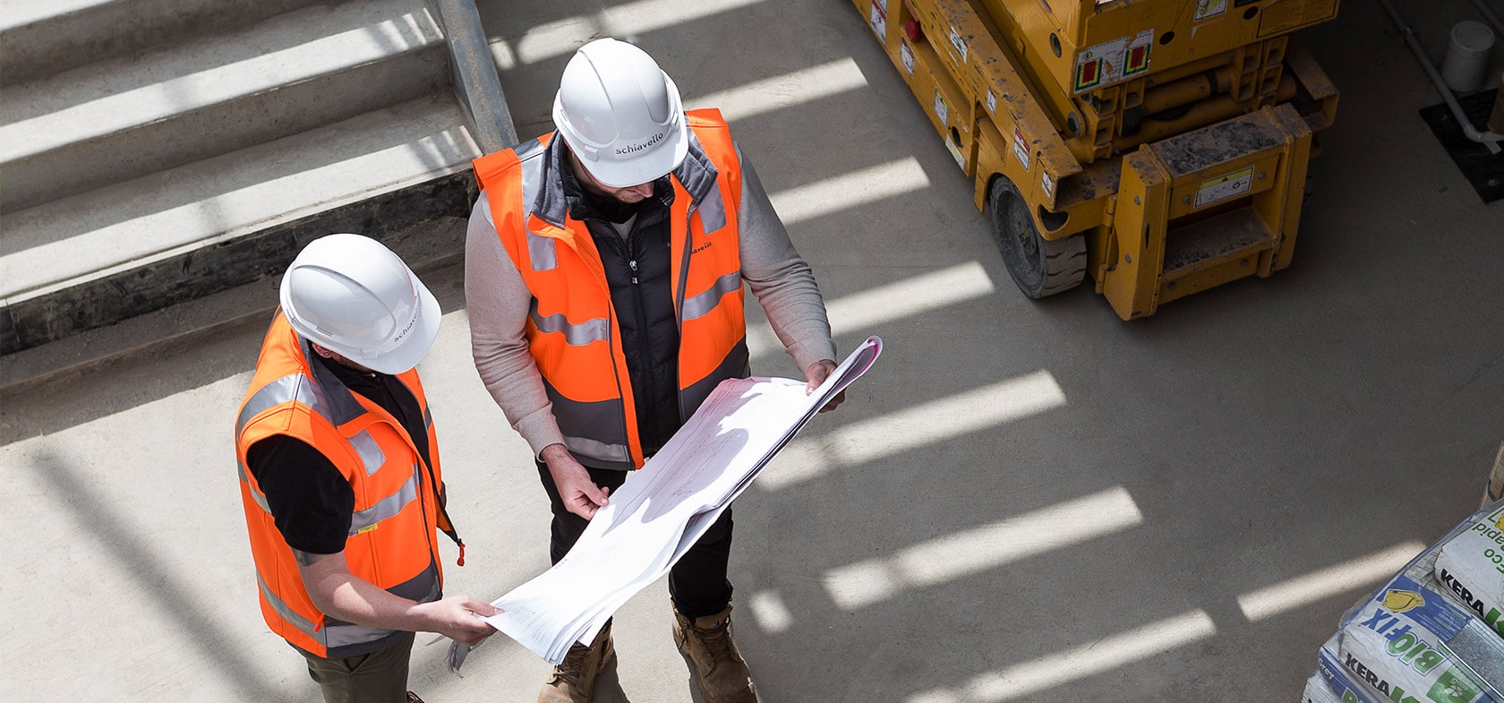 schiavello construction company in melbourne site managers wearing construction hardhats looking at plans on site